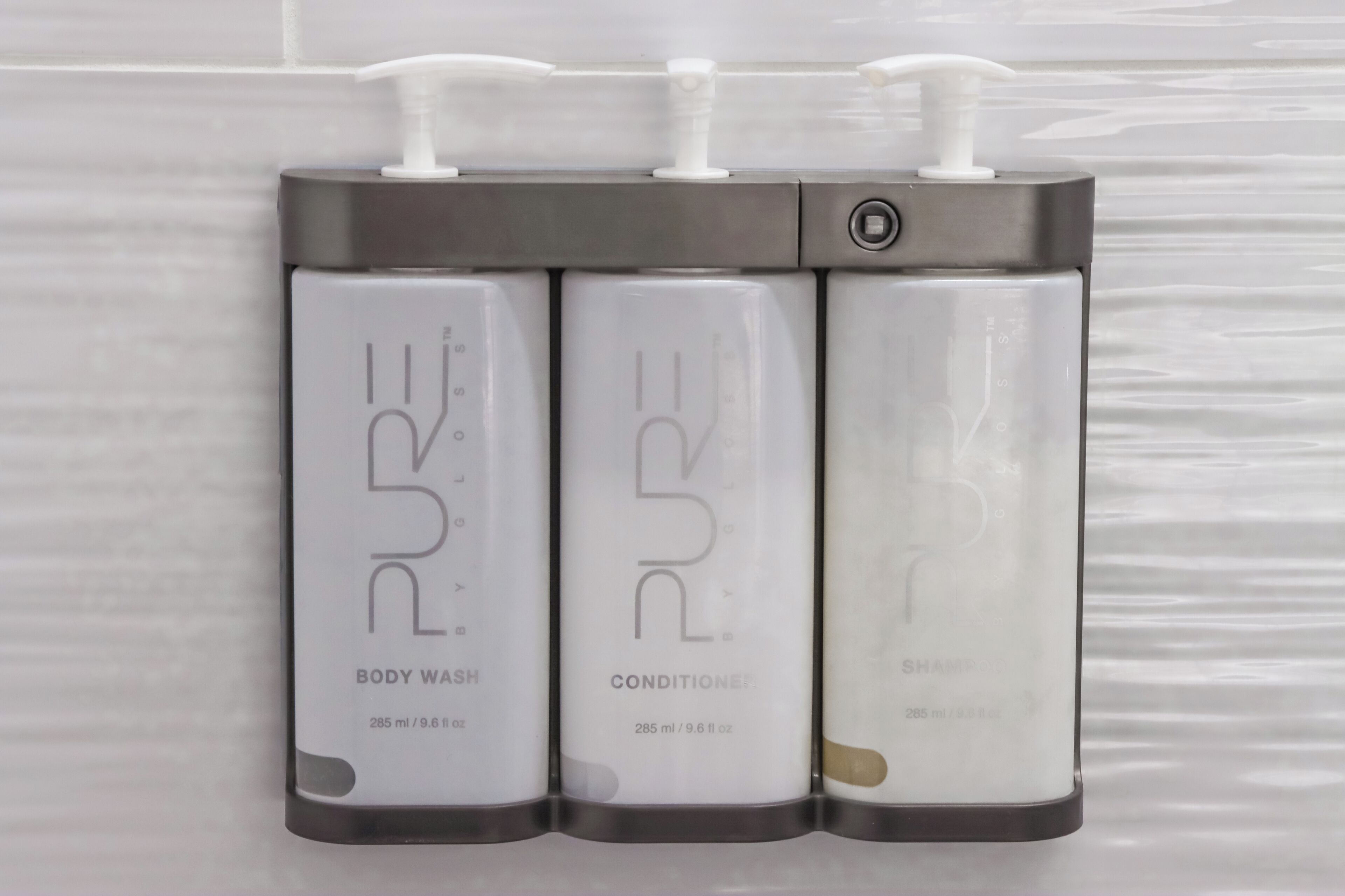 Tres botellas de agua de baño, acondicionador y champú PURE.