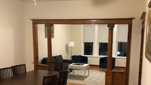 A dining area with a wooden table and chairs, a ceiling fan, and a view into a living room with a sofa and a lamp. - Walk to Wrigley Field/Monthly Discounts Available (Chicago)