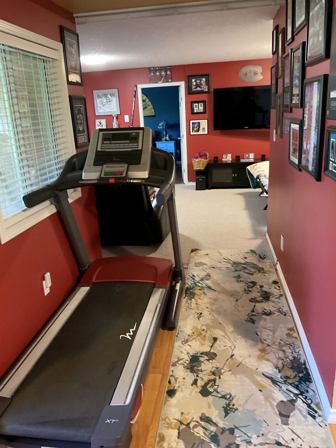 A home gym with a treadmill, a small desk, and a chair.