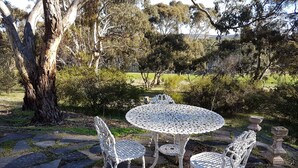 A round outdoor table with four chairs, surrounded by stone paving and greenery. - Bronte Manor, Wuthering Heights ~ min. 4 people - dog friendly (Clare)