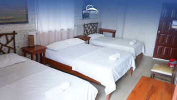 Quarto de hotel com três camas de solteiro, cabeceiras de madeira e uma pequena mesa de madeira.