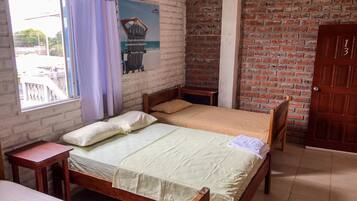 Een kamer met een houten bed, een klein houten tafeltje, een raam met gordijnen, een bakstenen muur en een deur.
