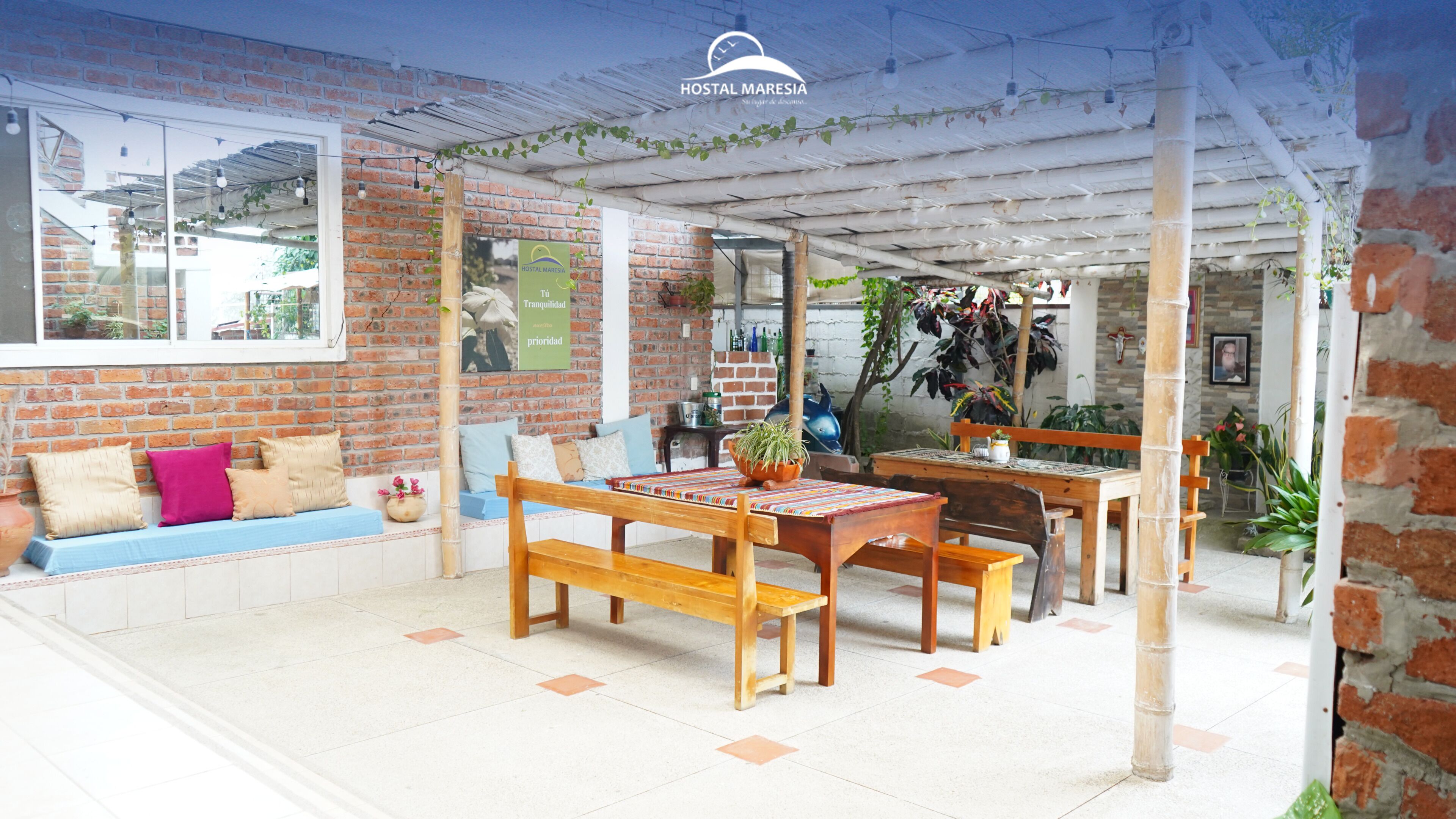 Un patio acogedor con pared de ladrillo, muebles de madera e iluminación colgante en el techo.