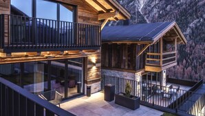 A modern mountain lodge with a wooden exterior, large windows, and a balcony with a view of the surrounding mountains. - Melisande 3 by Interhome (Sölden)