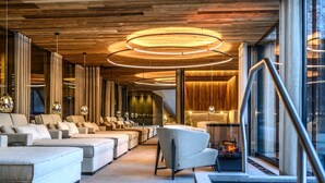 A modern interior with a long row of sofas and armchairs, a fireplace, and a large window with a view. - Melisande 3 by Interhome (Sölden)