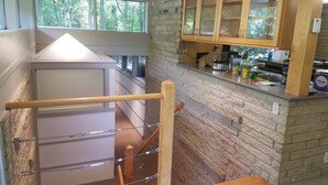 Una cocina con salpicadero de piedra, armarios de madera y ventana con vistas a árboles.