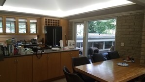 Una cocina moderna con armarios de madera, un refrigerador negro y un comedor con mesa y sillas de madera.