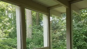 Un baño con bañera y ventanas amplias que dan a un jardín exuberante.