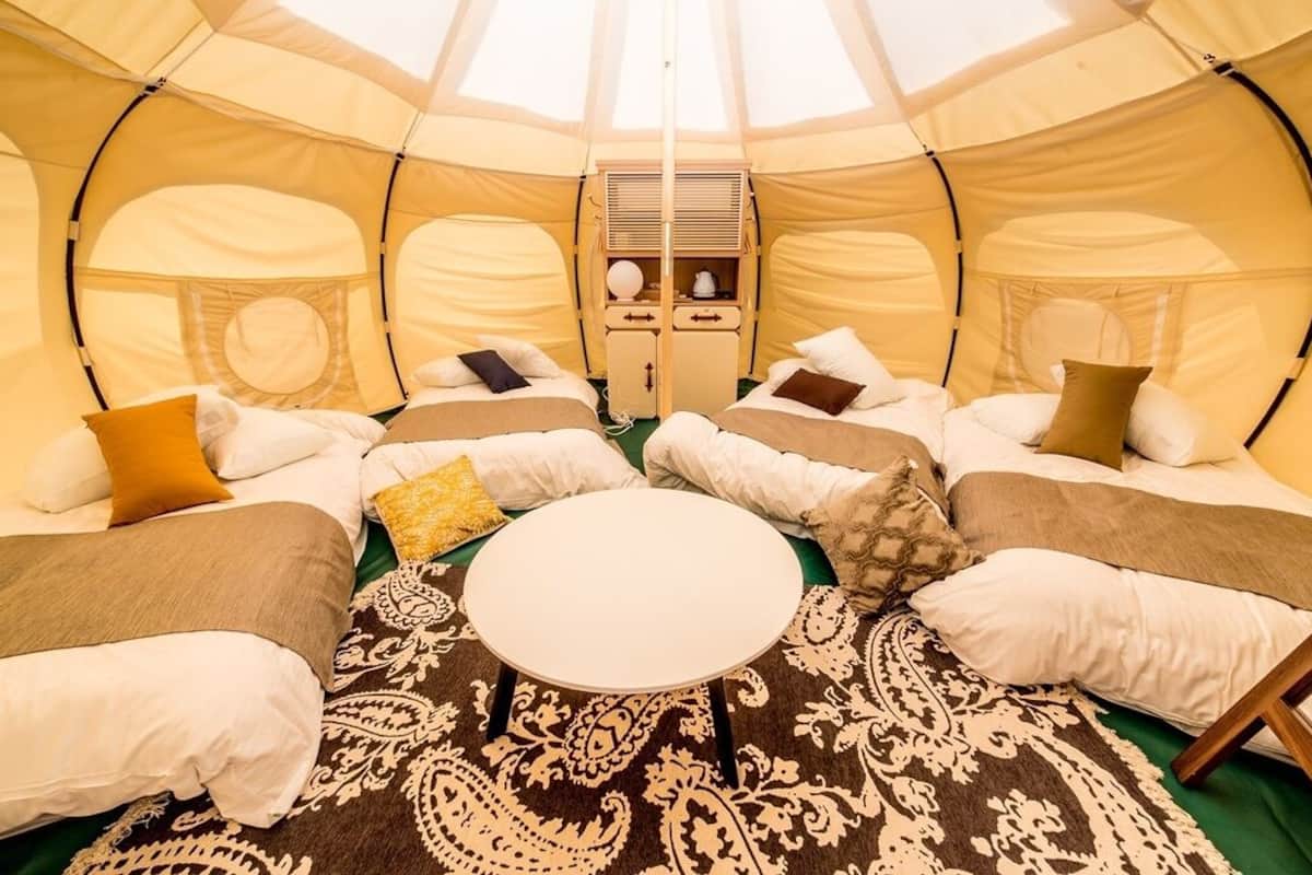 A tent with two beds, a central table, and a storage unit.