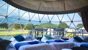 Una habitación con dos camas, una mesita y vistas a un lago y montañas.