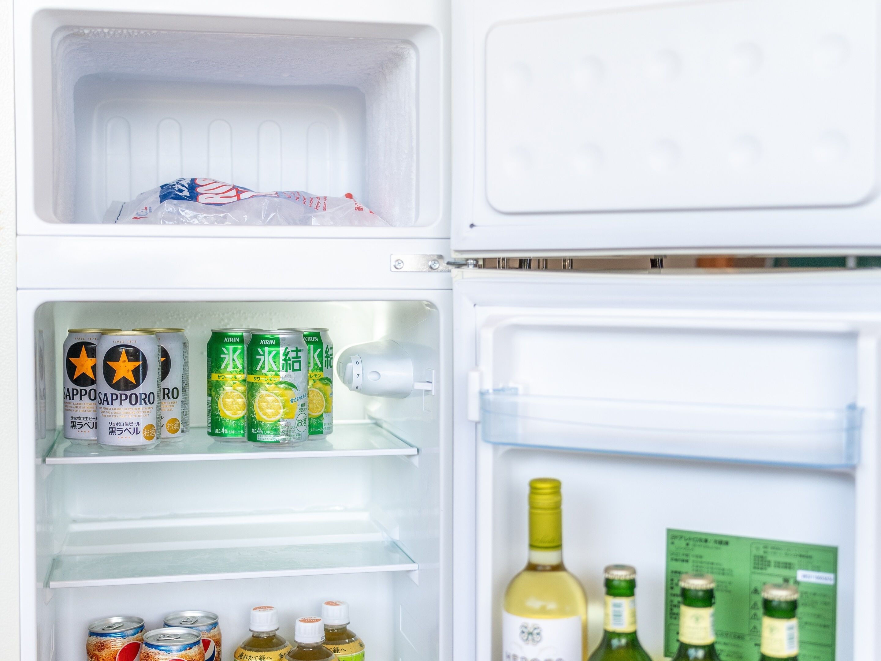 An open refrigerator with beverages and bottles.