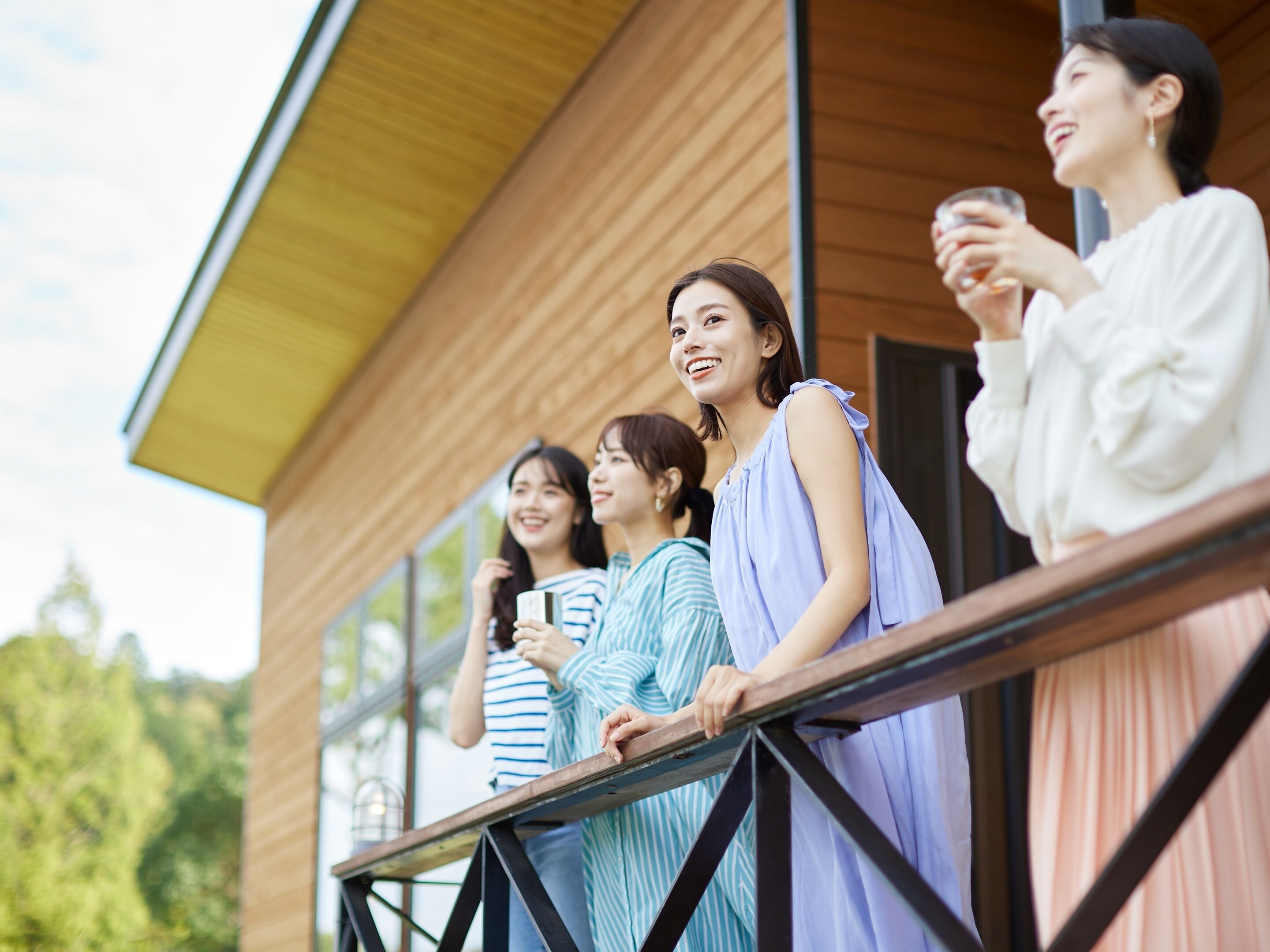 A group of people standing on a wooden balcony with a metal railing.
