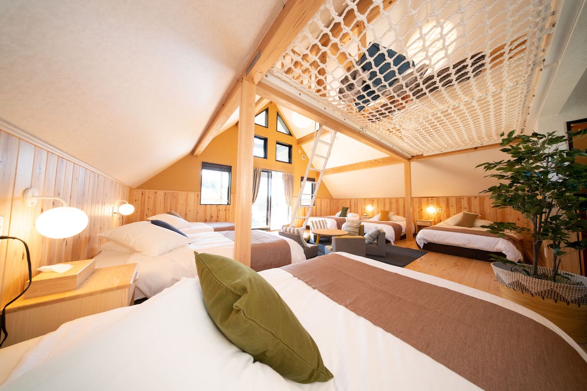 A cozy, well-lit attic bedroom with wooden walls, multiple beds, and a skylight.