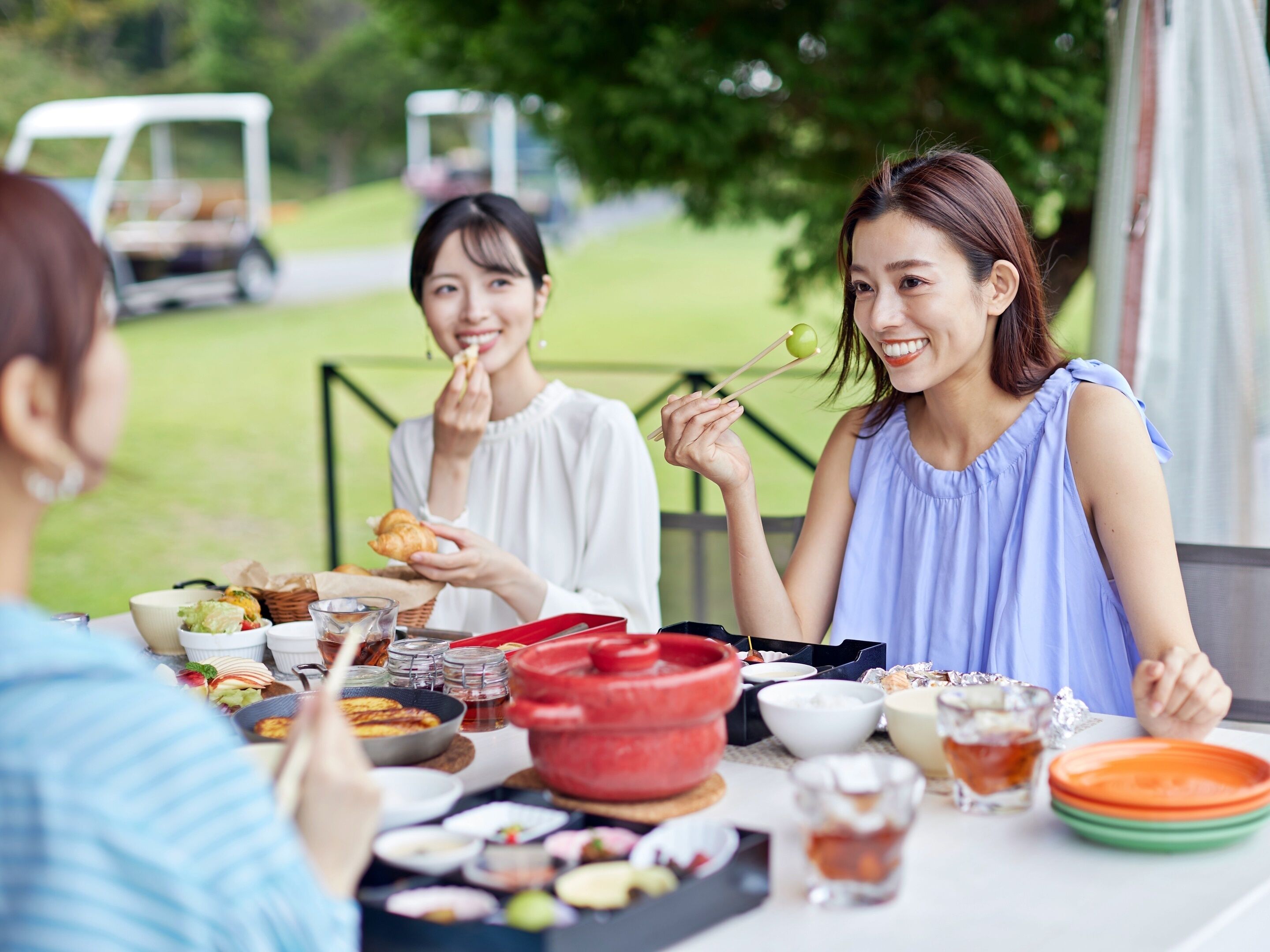 A group of people dining outdoors at a table with various dishes and drinks.
