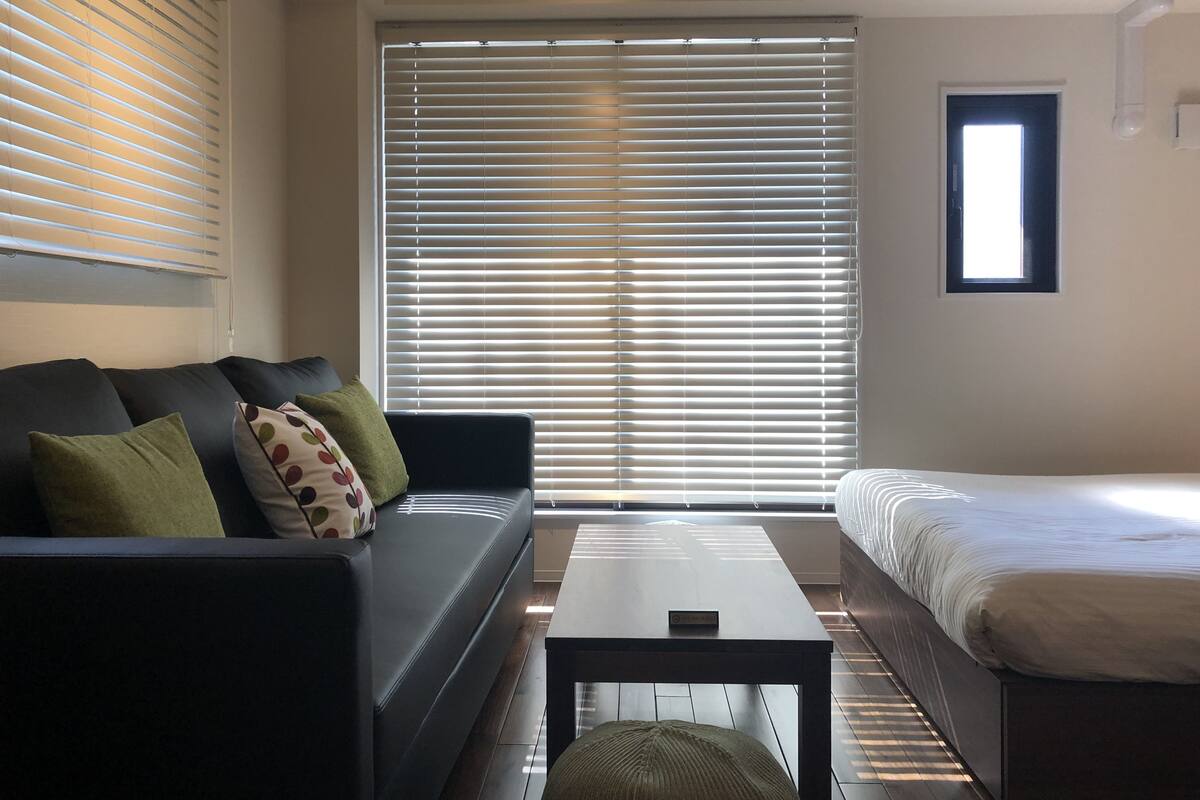 Ein modernes Schlafzimmer mit einer schwarzen Couch, einem kleinen Tisch und einem Bett.