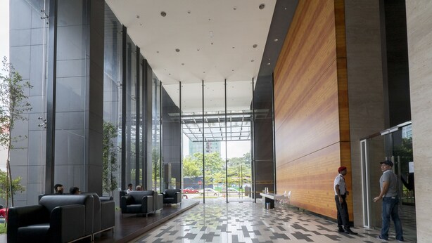 Een moderne lobby met een geruit vloerkleed, zitgedeeltes en een grote glazen wand met uitzicht op buiten.