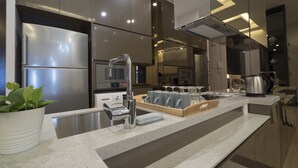 Een moderne keuken met roestvrijstalen apparatuur, een centraal eiland met een spoelbak en een potplant.