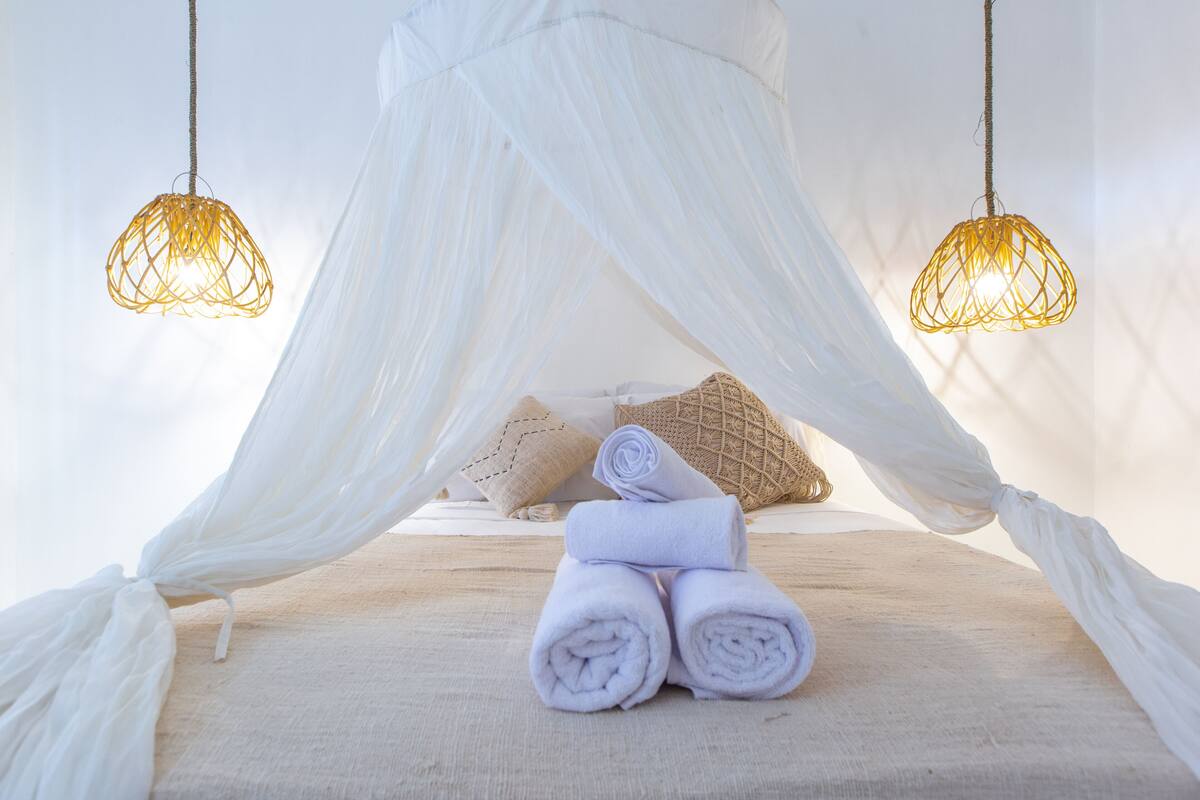Een hemelbed, twee hangende lampen en opgerolde handdoeken.