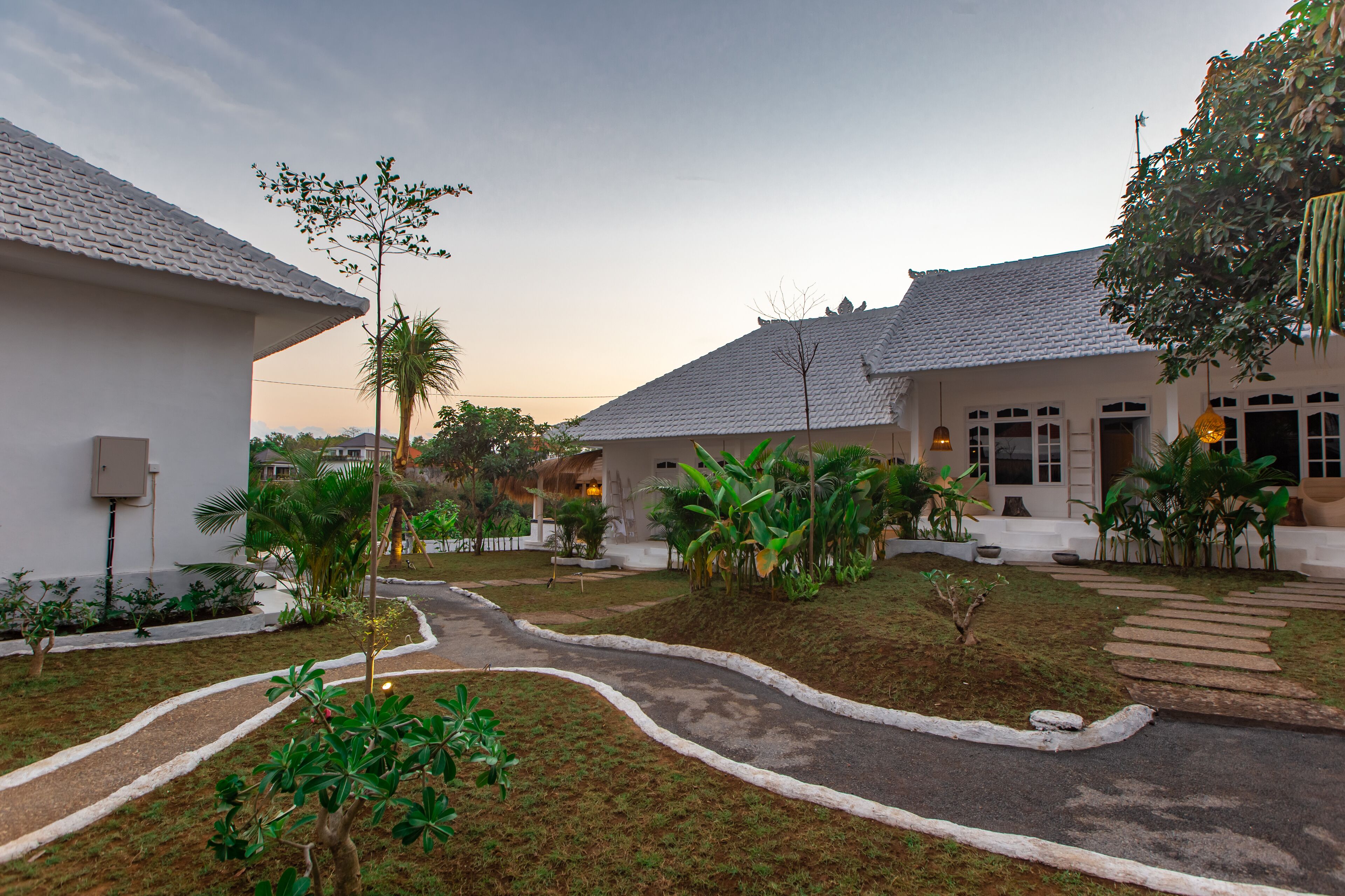 A courtyard with a pathway leading to a building with a tiled roof.