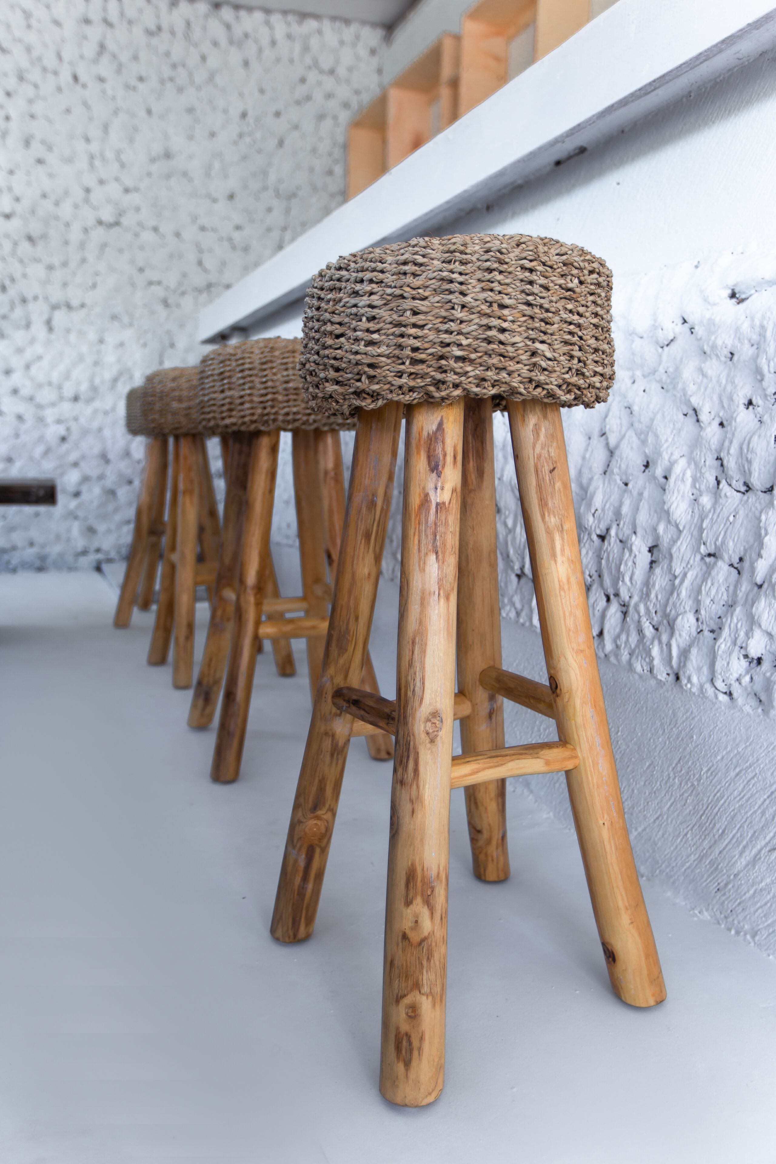 A row of wooden stools with woven seats.