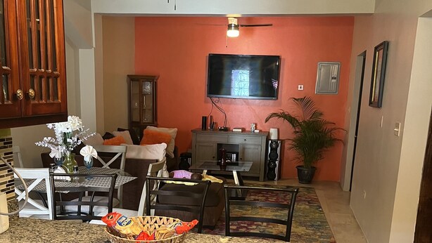 Eine Küche mit Granit Arbeitsplatten, Holzausstattung, Deckenventilator, Fernseher und einem Essbereich mit Stühlen und Tisch.