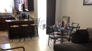 Ein geräumiges Wohnzimmer mit einer dunkelgrauen Couch und einem Essbereich mit Tisch für vier Personen.