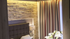 Habitación de hotel con una cama grande, una mesita de noche, una lámpara y un panel de madera en la pared.