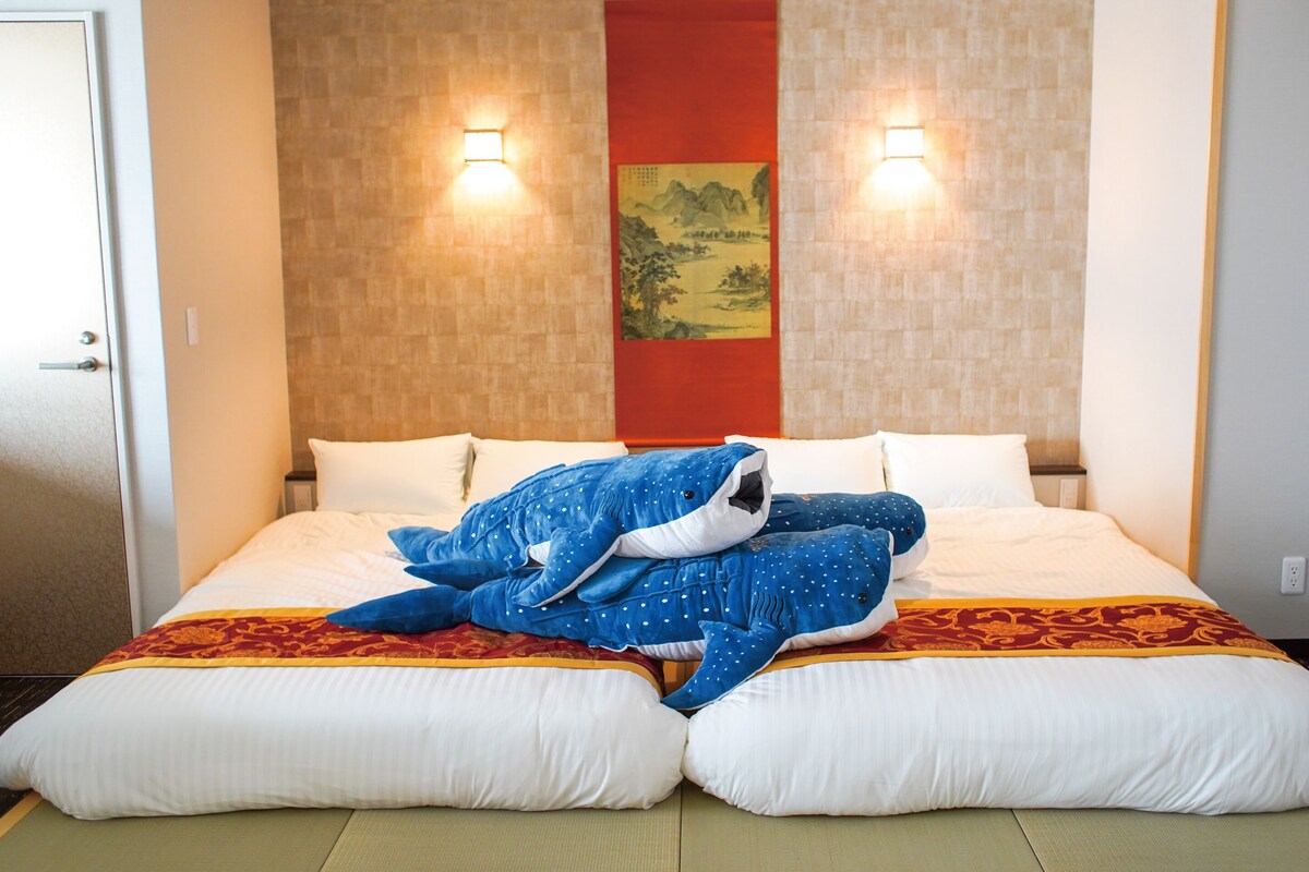 Une chambre d’hôtel avec un lit, des oreillers, une couverture et un luminaire fixé au mur.