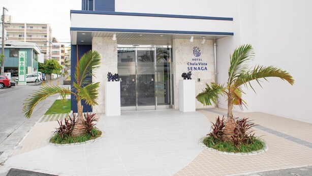 L’extérieur de l’hôtel Chula Vista Senaga se distingue par sa façade moderne, son entrée en verre et les deux palmiers qui se trouvent devant.