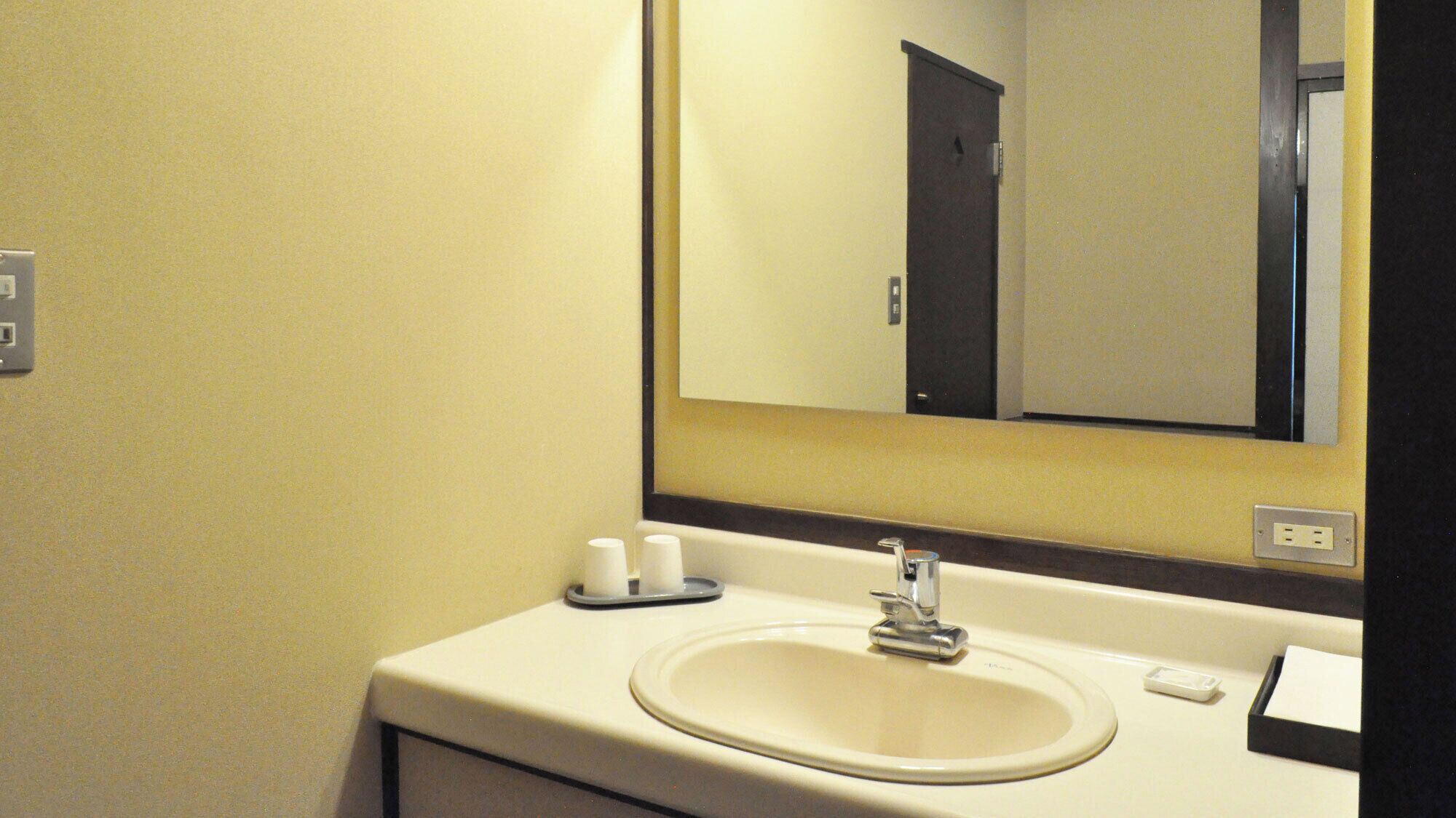 A bathroom with a sink, mirror, and toiletries.