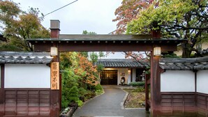 Een traditionele Japanse poort met een pad dat leidt naar een gebouw met een pannendak.