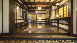 Een traditioneel Japans interieur met tatami vloerbedekking, houten balken en een gang naar een kamer met een schuifdeur.