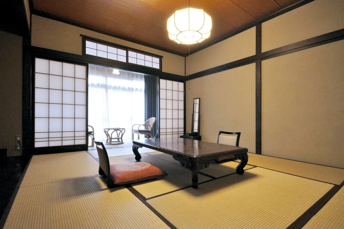 Une pièce de style japonais traditionnel, avec un sol recouvert de tatamis, une table basse et des portes coulissantes.