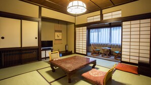 Een traditionele Japanse kamer met tatami vloerbedekking, een lage tafel, kussens en schuifdeuren.