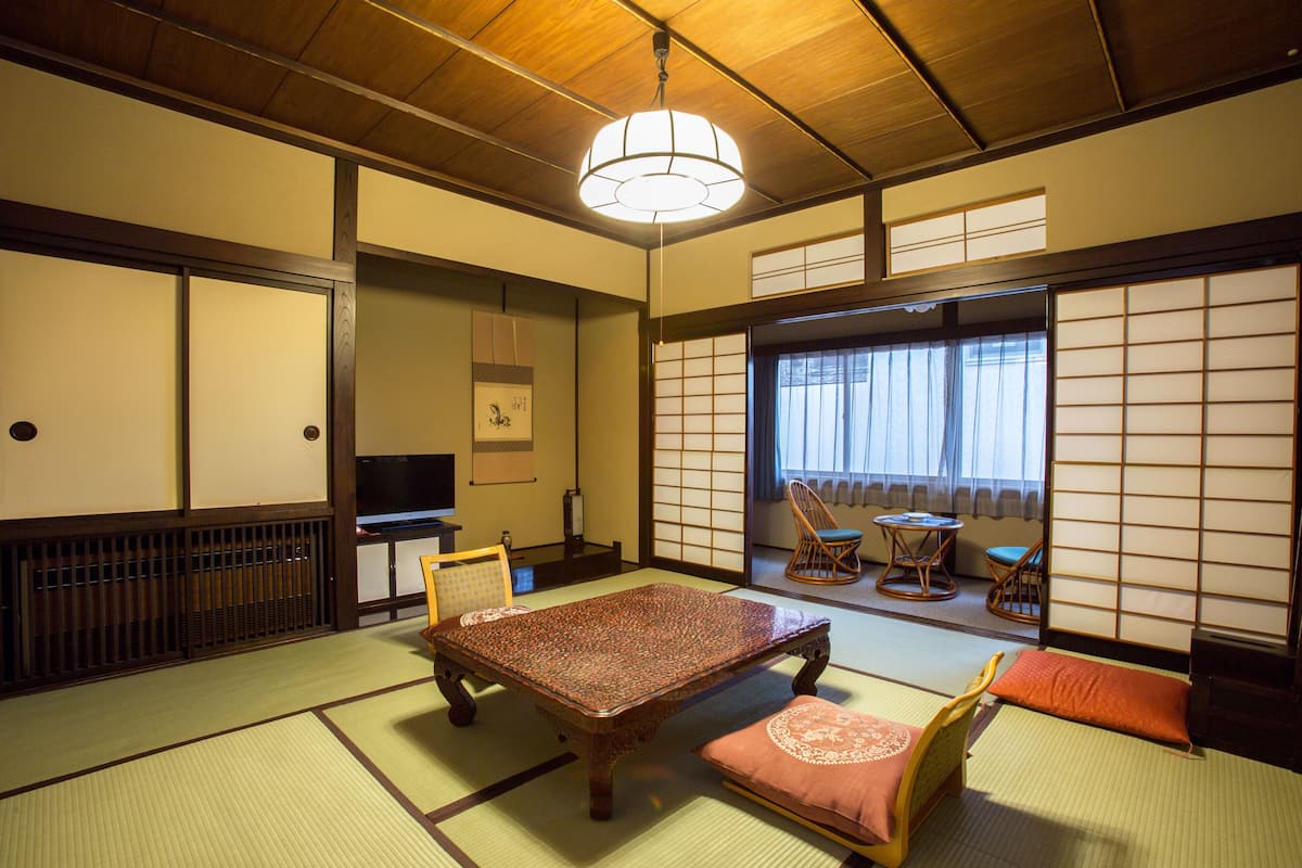 Une pièce de style japonais traditionnel, avec un sol recouvert de tatamis, une table basse, des coussins et des portes coulissantes.