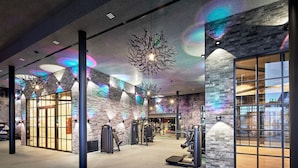 Une salle de sport équipée de matériel d’exercice, avec un mur en briques et une grande fenêtre.