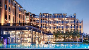 Un hôtel moderne doté d’une façade en verre, d’une piscine extérieure et de nombreux balcons.