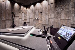 A modern room with a large desk, a bike, and a control panel. - SINGLE ROOM CLASSIC - 5* Wellness & Sporthotel Jagdhof (Röhrnbach)