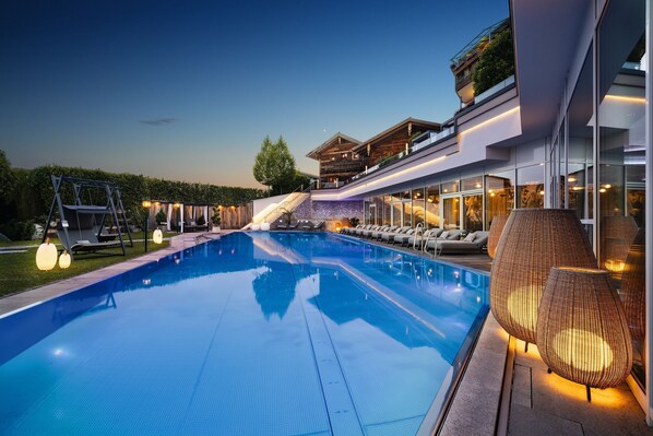 Un hotel moderno con piscina, zona de estar exterior y una escalera que lleva al segundo piso.