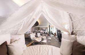 A modern interior with a central seating area, a large window, and a distinctive ceiling design. - DREAM SUITE - 5* Wellness & Sporthotel Jagdhof (Röhrnbach)