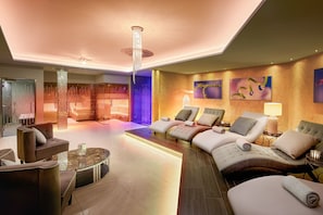 A modern hotel lobby with a seating area, a reception desk, and a large chandelier.