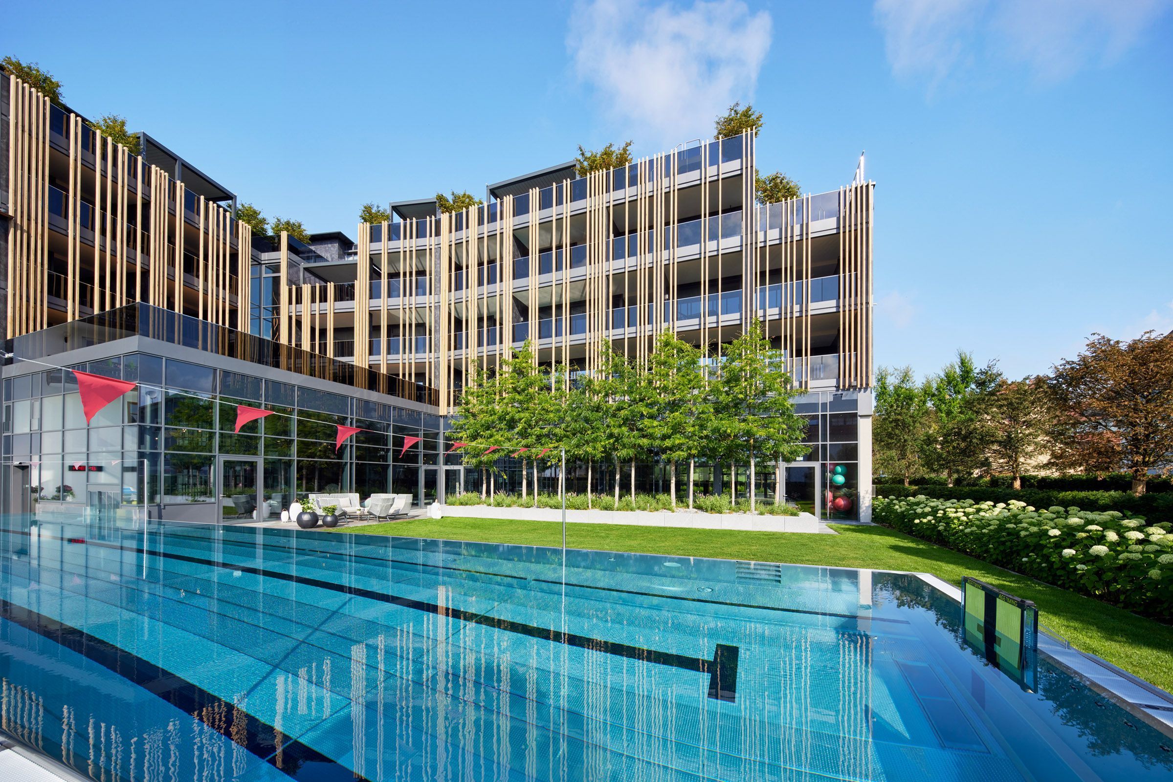 Ein modernes Hotel mit Pool, mehreren Balkonen und einem gepflegten Garten.