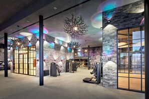 Une salle de sport équipée de matériel d’exercice, avec un mur en briques et une grande fenêtre.