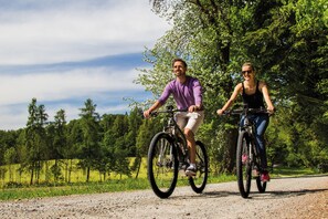 Two people riding bicycles on a gravel path surrounded by trees. - DOUBLE ROOM BERGKRISTALL - 5* Wellness & Sporthotel Jagdhof (Röhrnbach)