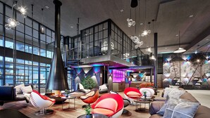 A spacious lobby with modern seating, a large window, and a staircase leading to an upper level.