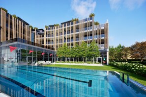 A modern hotel with a swimming pool, multiple balconies, and a well-maintained garden. - JAGDHOF-SUITE - 5* Wellness- & Sporthotel Jagdhof (Röhrnbach)
