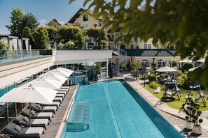 A swimming pool with sun loungers, a glass balustrade, and a staircase leading to a second floor. - JAGDHOF-SUITE - 5* Wellness- & Sporthotel Jagdhof (Röhrnbach)