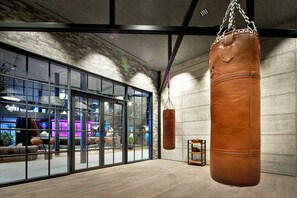 A spacious room with large windows, a punching bag, and a wooden floor.