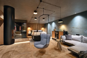 A modern interior with a hanging chair, a sofa, and a bed in the background.