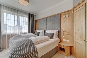 Ein Schlafzimmer mit einem Bett, Nachttischen, einem Kleiderschrank und einem Fenster mit Vorhängen.